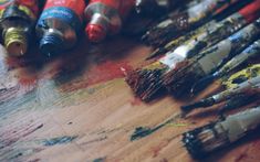 many different colored paint brushes are on the table