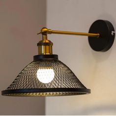 a black and gold wall light with a white heart on the bulb is hanging from an arm