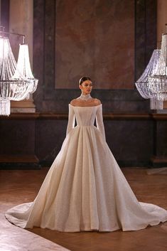 a woman in a white wedding dress standing on a stage with chandeliers behind her