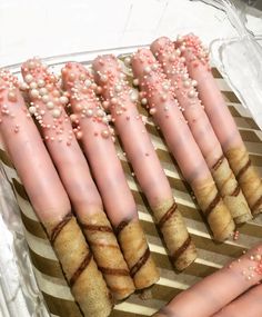 there are many pink and white candles with sprinkles on them in a tray