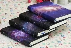 three books are stacked on top of each other, with the covers painted purple and blue