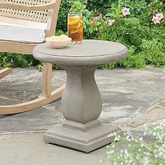 a chair and table sitting on a stone patio with flowers in the backgroud