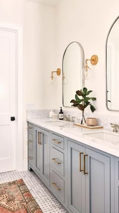 a bathroom with two sinks, mirrors and a rug on the floor in front of it