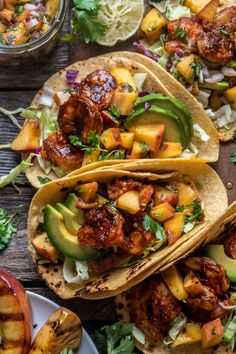 three tacos filled with meat and vegetables on top of a wooden table