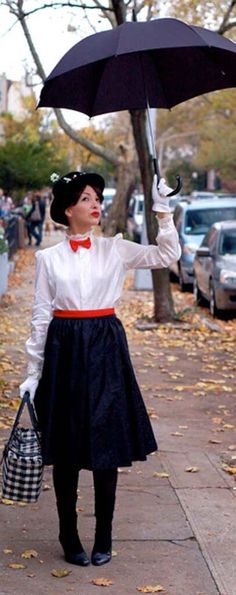 a woman holding an umbrella while standing on a sidewalk