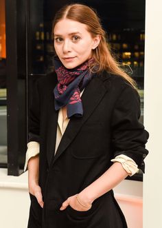 a woman standing in front of a window wearing a black suit