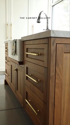 the cabinetry in this kitchen is made of wood and has brass pulls on each drawer