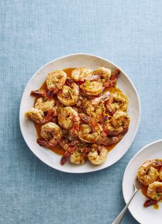 two white plates filled with cooked shrimp and sauce on top of a blue tablecloth