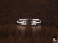 two white gold engagement rings on a wooden table