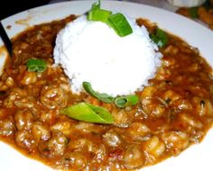 a white plate topped with pasta and meat covered in sauce, garnished with sour cream