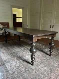 a large wooden table sitting on top of a rug in front of a white door