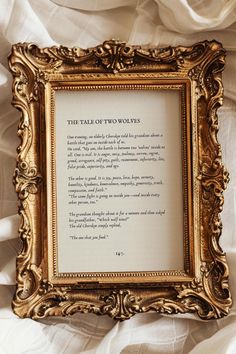 an ornate gold frame with a poem written in it on top of white cloths