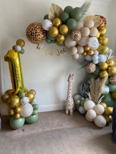 the balloon arch is decorated with gold, green and white balloons that spell out one