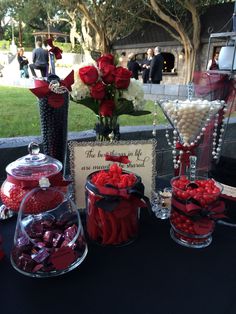 a table topped with lots of candy and candies next to a vase filled with roses