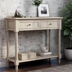 a white table with two drawers and a potted plant on it next to a brick wall