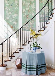 there is a table with a blue cloth on it next to the stairs and flowers