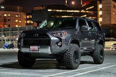 a gray toyota 4runner is parked in the parking lot at night with its lights on