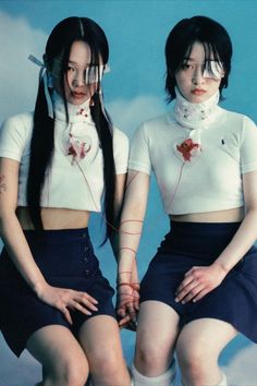 two young women sitting on top of each other with headphones in their ears and wearing short skirts