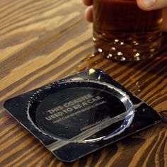 a person is holding a glass on a wooden table