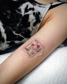 a woman's arm with a tattoo on it that has stamps and flowers on it