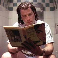 a man sitting on the toilet reading a book