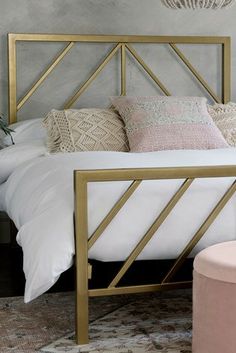 a white bed with gold frame and pillows