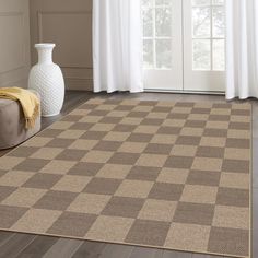 a brown and tan checkered rug in front of a white vase on the floor