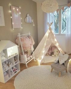 a child's bedroom with a teepee tent and lights on the wall above it