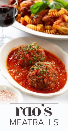 two plates with meatballs and pasta on them next to a glass of red wine