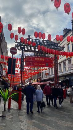 people are walking under red lanterns on the street