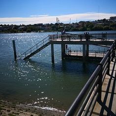 a man standing on a pier next to the water