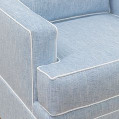 an upholstered blue couch with white piping on the arm and back ends