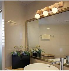 a bathroom sink sitting under a mirror next to a light above it's faucet