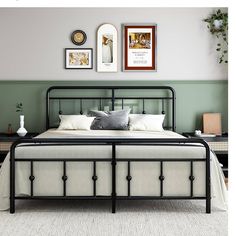 a black metal bed frame with white pillows and throw pillows on the headboard, along with two framed pictures above it