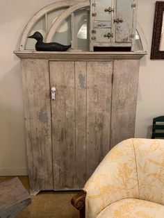 an old wooden cabinet sitting next to a chair in a room with a mirror on the wall