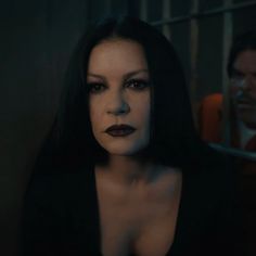 a woman with long black hair standing in front of a jail cell