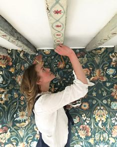 a woman is working on the ceiling in her home