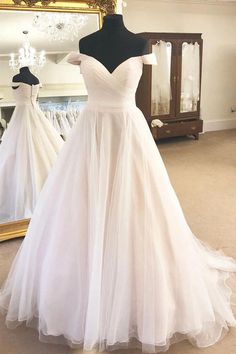 a white wedding dress is on display in front of a mirror and mannequins