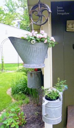 two buckets with flowers hanging from them on the side of a building next to a door