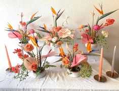 three vases with flowers and candles on a table