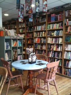 there is a table and chairs in the room with many bookshelves behind it