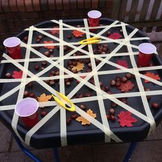 an outdoor game made out of sticks and plastic cups with fall leaves on them, sitting on a table