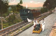 two men ride in a small cart on the railroad tracks as a train passes by