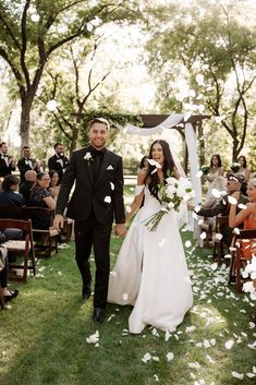 a bride and groom walk down the aisle as confetti flies in the air