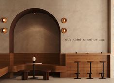 the interior of a restaurant with wooden tables and stools in front of an arched wall