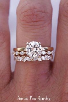 a woman's hand with a diamond ring on top of her finger and the other hand holding an engagement ring