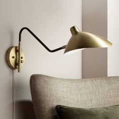 a wall lamp on the side of a couch in a living room with pink walls