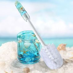 a toothbrush sitting on top of a glass filled with water next to shells and starfish