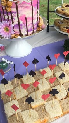 a table topped with lots of food next to a cake and cupcakes on sticks