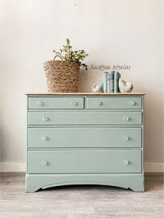 a blue dresser with books and a basket on top